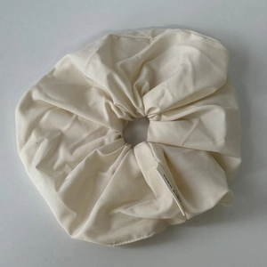 Macro detail of cream fabric scrunchie texture with a black and white hand made label