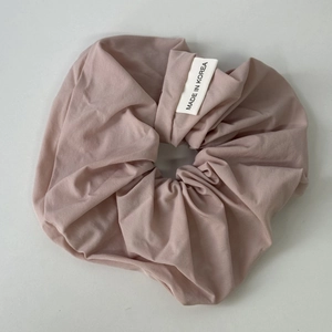 Close-up of dusty pink matte fabric hair scrunchie with a Made in Korea woven label