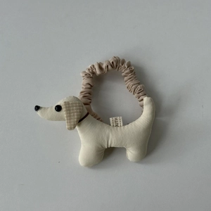 Détail de la pince à cheveux teckel en tissu avec texture beige et oreilles à carreaux