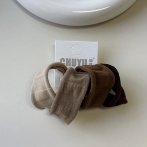 Detailed close-up of 4-pack earth tone elastic hair ties on minimalist card packaging