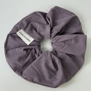 Detailed macro view of dark purple matte scrunchie with soft ruffled fabric texture