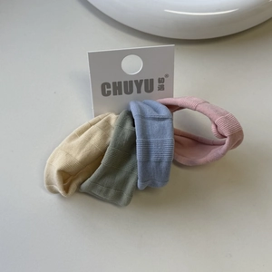 Detail showing set of four ribbed knitted hair scrunchies in muted tones on display card