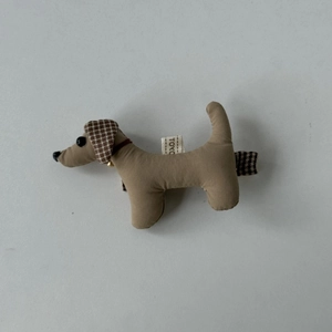 Détail d'une pince à cheveux en tissu chien avec petite clochette dorée et étiquette