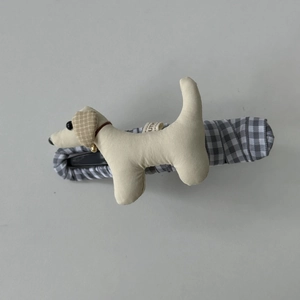 Détail d'une pince à cheveux chiot en peluche avec base recouverte de tissu et clochette
