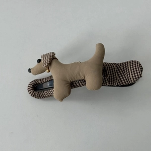 Détail de la pince à cheveux en peluche teckel en tissu kaki avec oreilles à carreaux