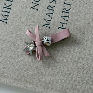 Dettaglio fermaglio per capelli con fiocco rosa, stella di strass e ciondolo nuvola argento