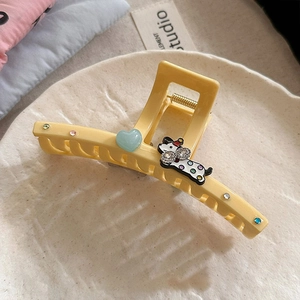 Détail d'une pince à cheveux jaune avec cœur bleu et motif de petit chien mignon à pois