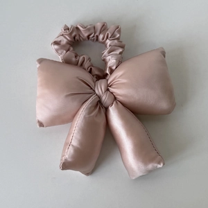 Vue détaillée d'un chouchou noeud en satin doré champagne avec texture soyeuse