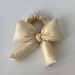 Détail d'un chouchou noeud en satin champagne moelleux avec une texture soyeuse