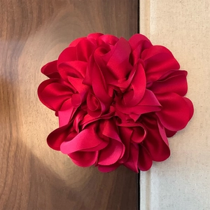 Detailaufnahme eines Haargummis aus rotem Satin mit fein geschichteten Blütenblättern