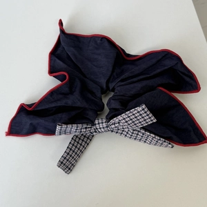 Macro view of navy blue bow scrunchie with red trim and black-white plaid center