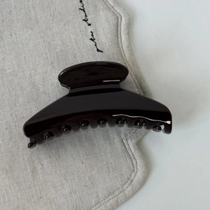 Pince à cheveux marron glacé avec finition miroir sur tissu en lin beige