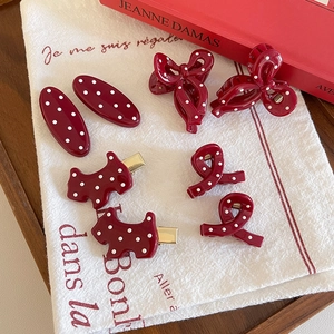 Elegant burgundy polka dot hair clips set including bow and dog shapes on white linen fabric