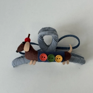 Detalle de pinza para el pelo denim azul con perro salchicha de peluche y botones de colores