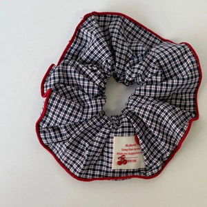 Detailed macro view of navy plaid hair scrunchie with red edges and textile label
