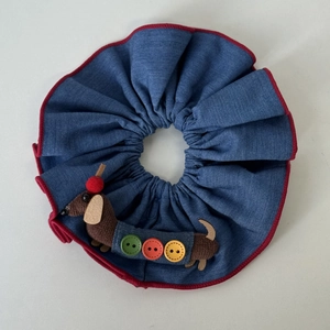 Detalle de coletero denim azul con parche de perro salchicha y botones de colores