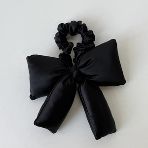 Détail d'un grand chouchou nœud bouffant en satin noir avec un lustre doux et des coutures denses