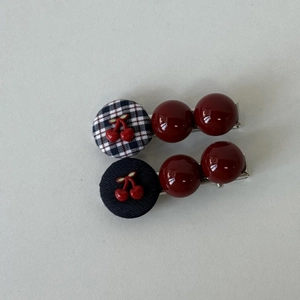 Detail of vintage cherry hair clips with red bead accents and plaid fabric base