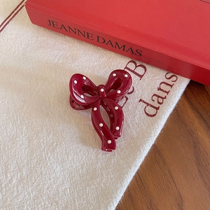 Detailed view of a vintage dark red bow hair clip with white polka dots on fabric