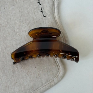 Détail de la pince à cheveux ambrée montrant la texture acrylique brillante et les dents