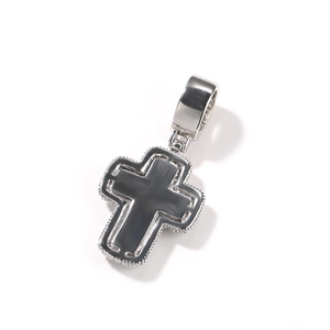 Détail d'un pendentif croix hip-hop argenté avec incrustation noire et bordure perlée