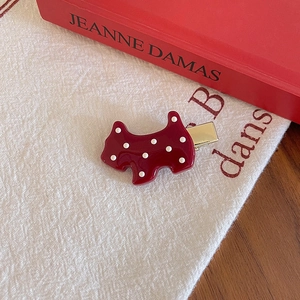 Detailed shot of dark red polka dot dog hair clip on a vintage French fabric background