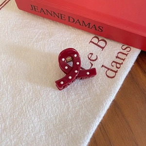 Close-up of twisted ribbon hair claw clip in red with white polka dots on linen