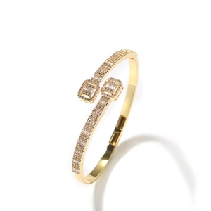 Detailed close-up of a gold-plated bypass bracelet with pave-set baguette and round zircons