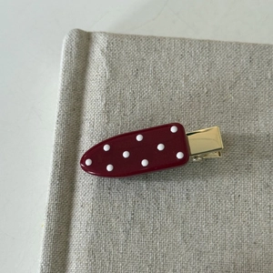 Close-up of burgundy polka dot hair clip on gold metal alligator base with resin finish