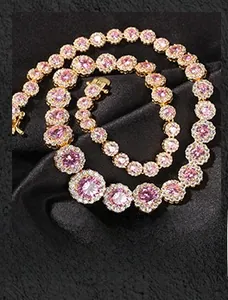 Close-up of golden tennis necklace featuring round pink cubic zirconia on black fabric
