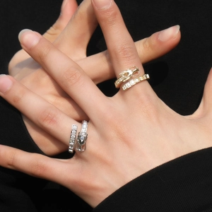 Detail of adjustable dragon rings in gold and silver set with sparkling zircon stones