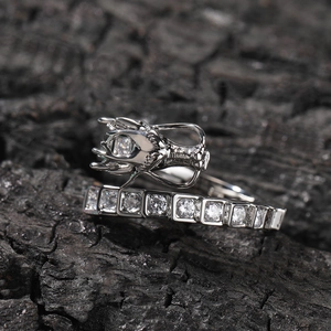 Detailed close-up of a dragon head ring with sparkling cubic zirconia on charred wood