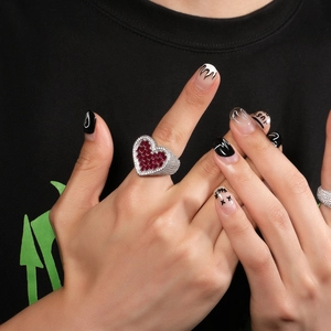 Detail of hip-hop silver ring with heart-shaped red stone and pave zircon setting