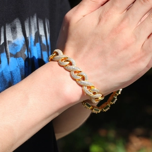 Close-up of gold iced-out Cuban link bracelet with white zircons on a man wrist