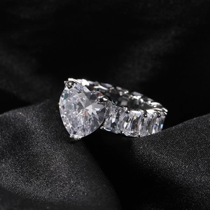 Macro view of heart-cut cubic zirconia ring with baguette side stones on black silk