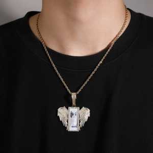 Detail of hip hop gold necklace with iced out wings and rectangle photo locket on rope chain