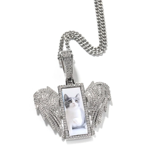 Macro view of iced out silver rectangular angel wing photo pendant on cuban link chain