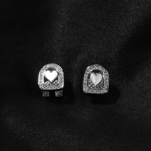 Gros plan de boucles d'oreilles cœur en nacre et diamants sur un fond de soie noire