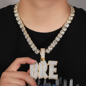 Dettaglio del ciondolo hip hop BRE in oro con zirconi su un modello maschile