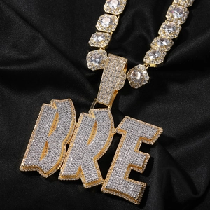 Dettaglio macro del ciondolo hip-hop BRE dorato con micro-pavé di zirconi cubici