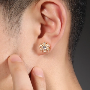 Macro shot of gold snowflake magnetic earring with white zircon inlay worn on ear
