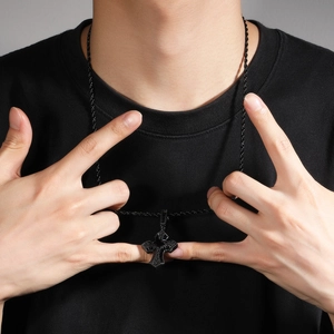 Detalle de colgante de cruz hip hop con circonitas negras y cadena de cuerda en modelo
