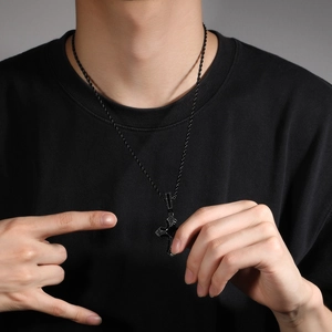 Detalle del collar con colgante de cruz negra hip hop con circón en un modelo masculino