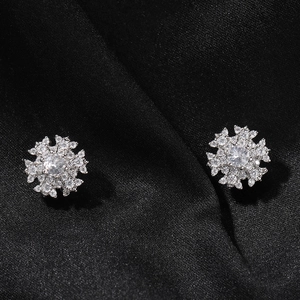 Macro shot of silver snowflake magnetic earrings with round cubic zirconia on black silk