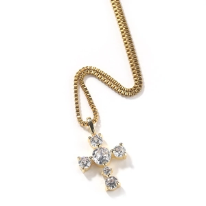 Detailed view of a gold cross pendant with claw-set round white cubic zirconia gems