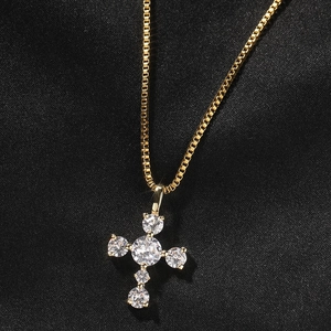 Detail of gold box chain necklace featuring a cross pendant with round zircons on silk