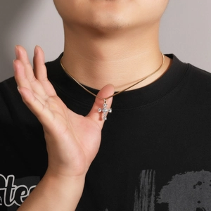 Detail of a gold cross pendant necklace with sparkling white crystals worn by a model