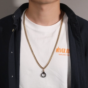 Close-up of golden Cuban link necklace with black circular pendant on a male model