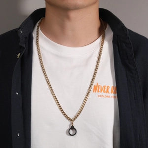 Close-up of a gold Cuban link chain with a black circular pendant on a male model