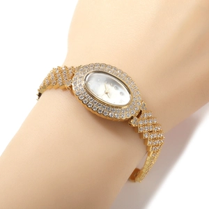 Détail du cadran ovale et du bracelet orné de zircons d'une montre de luxe dorée pour femme